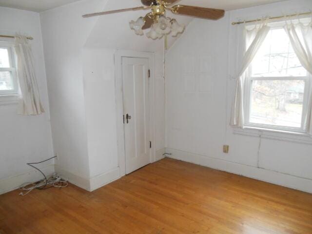 empty room featuring plenty of natural light, ceiling fan, and light wood-type flooring