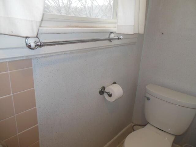 bathroom featuring tile walls and toilet