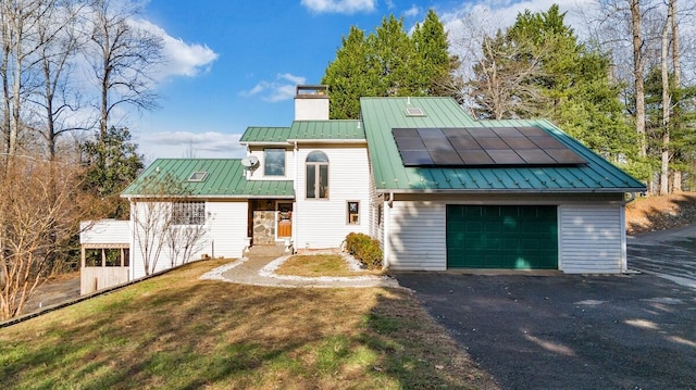 view of front of home with solar panels, a garage, and a front yard