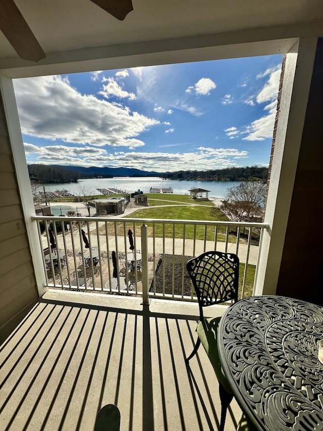 balcony with ceiling fan and a water view