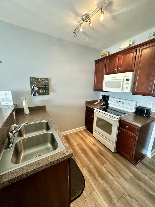 kitchen with white appliances, light hardwood / wood-style floors, track lighting, and sink