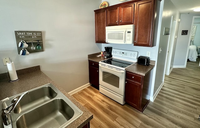 kitchen with white appliances, hardwood / wood-style flooring, and sink