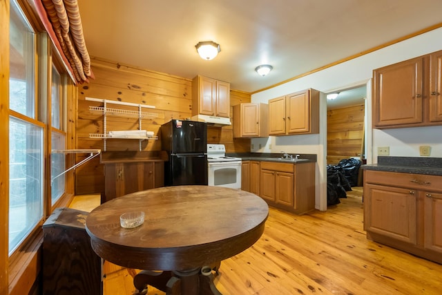 kitchen with light wood-type flooring, under cabinet range hood, dark countertops, freestanding refrigerator, and white range with electric stovetop