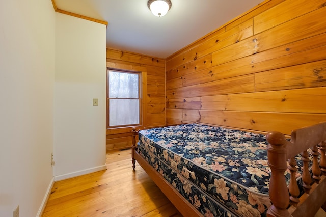 bedroom with wooden walls, light wood-style floors, and baseboards