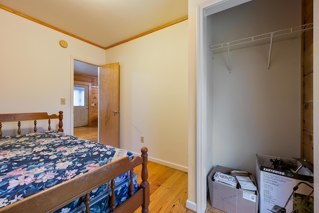 bedroom with crown molding, light wood-style flooring, and baseboards