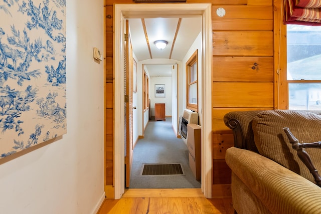 hall with visible vents, heating unit, plenty of natural light, light wood finished floors, and baseboards