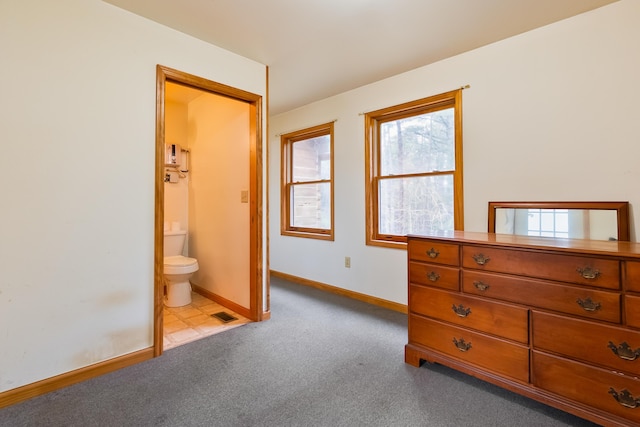 carpeted bedroom featuring visible vents, baseboards, and ensuite bathroom