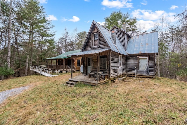 back of house with metal roof, a yard, a wooden deck, and a chimney