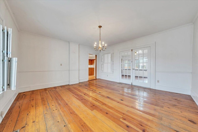 spare room with wood-type flooring, an inviting chandelier, and crown molding