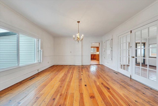 empty room featuring light wood-style flooring, crown molding, and an inviting chandelier