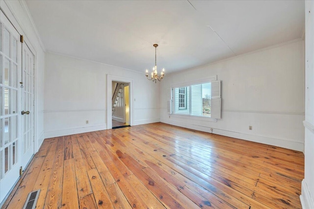 unfurnished room with visible vents, ornamental molding, light wood-style floors, an inviting chandelier, and baseboards