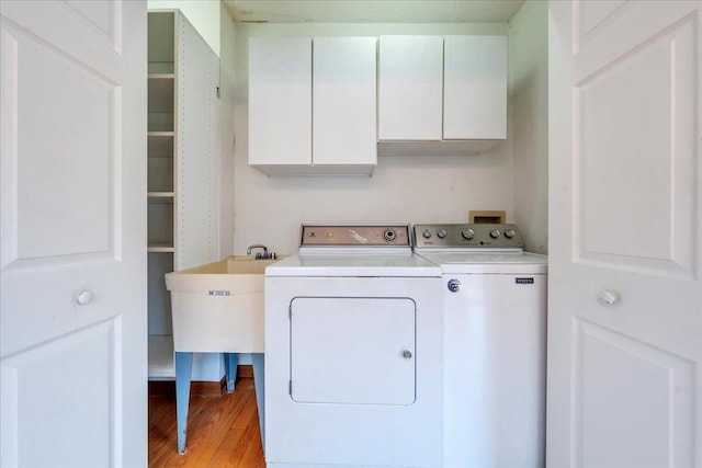 washroom featuring washer and clothes dryer, cabinet space, and light wood-style flooring