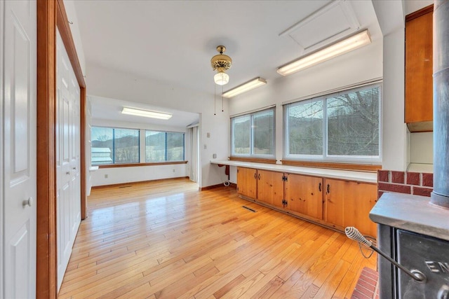 kitchen featuring visible vents, baseboards, light countertops, light wood-type flooring, and brown cabinetry