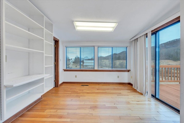 unfurnished room featuring light wood-type flooring, baseboards, and visible vents