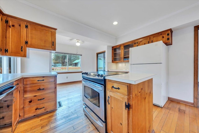 kitchen featuring dishwasher, light countertops, stainless steel range with electric cooktop, freestanding refrigerator, and brown cabinetry