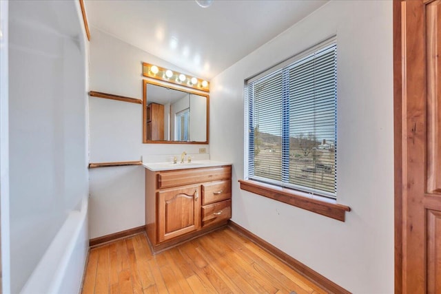 bathroom featuring hardwood / wood-style floors, vaulted ceiling, vanity, and baseboards