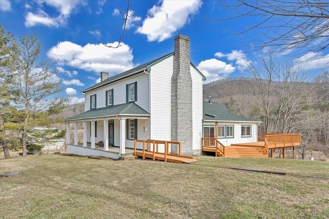 back of house with a shingled roof, a wooden deck, a yard, and a chimney