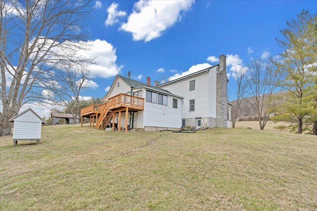 back of property with a wooden deck, a lawn, a chimney, and stairs