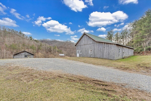 view of barn featuring a forest view, a yard, and fence