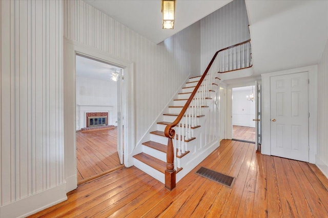 stairs with visible vents, a fireplace, and wood-type flooring