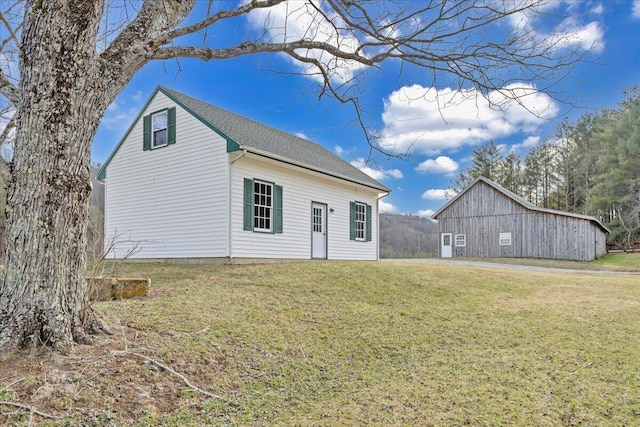 back of property featuring an outdoor structure, a yard, and a barn