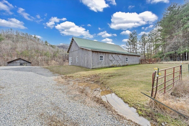 view of home's exterior featuring an outbuilding, fence, a yard, a barn, and metal roof