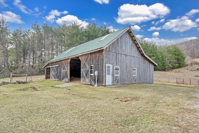 view of barn with a yard and fence