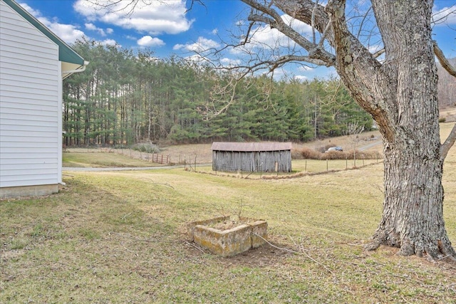 view of yard with fence, an outdoor structure, and a shed