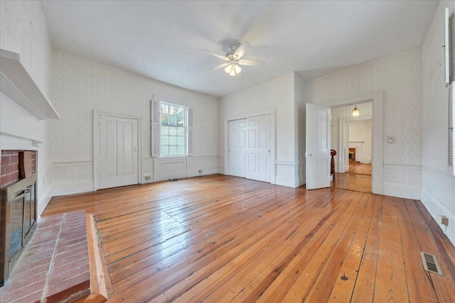 unfurnished living room with visible vents, a brick fireplace, and light wood-style floors