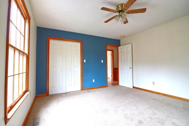 unfurnished bedroom with ceiling fan, carpet, and a closet