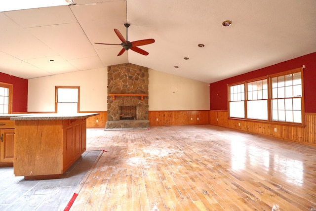 unfurnished living room with ceiling fan, a fireplace, light hardwood / wood-style floors, and vaulted ceiling