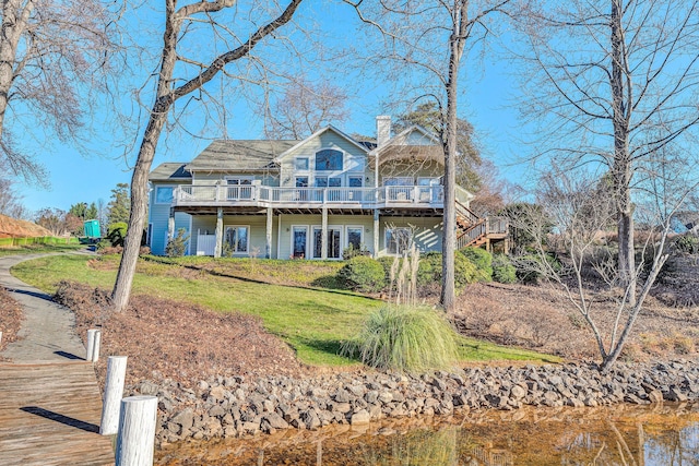 view of front of home with a deck with water view and a front lawn