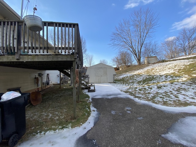 yard layered in snow with a shed and a deck