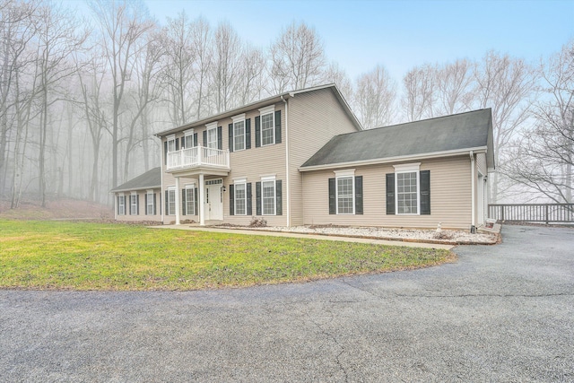 view of front of house with a front yard and a balcony