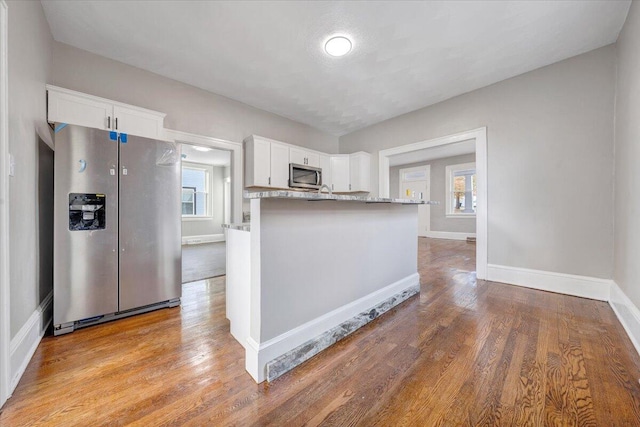 kitchen with white cabinets, light wood-type flooring, appliances with stainless steel finishes, and a healthy amount of sunlight