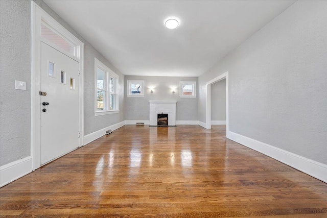 unfurnished living room featuring a brick fireplace and hardwood / wood-style floors