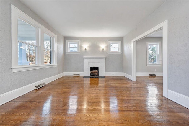 unfurnished living room with hardwood / wood-style flooring, plenty of natural light, and a fireplace