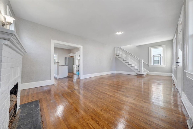 unfurnished living room with a brick fireplace and wood-type flooring