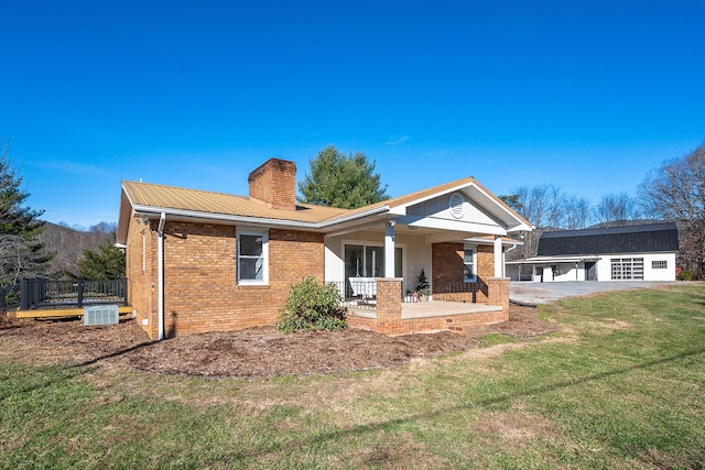 rear view of house featuring covered porch, a yard, an outbuilding, and central AC