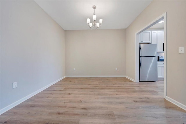 unfurnished dining area with light wood-type flooring and a chandelier