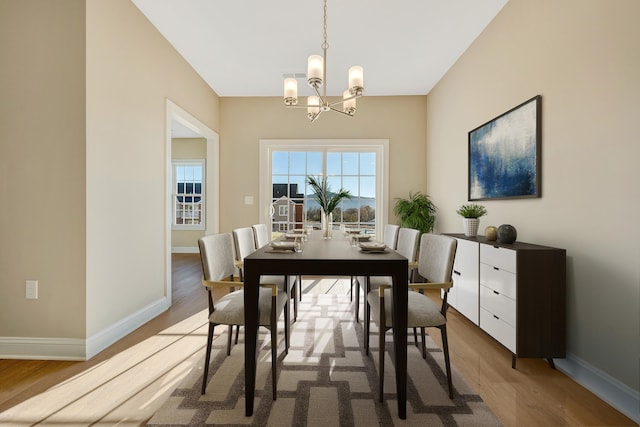 dining space featuring wood-type flooring and an inviting chandelier