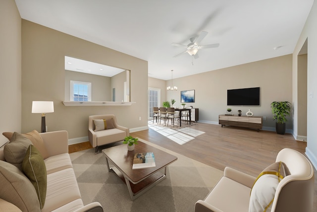 living room featuring ceiling fan with notable chandelier and light wood-type flooring