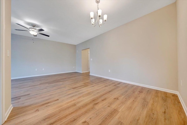 empty room featuring ceiling fan with notable chandelier and light wood-type flooring