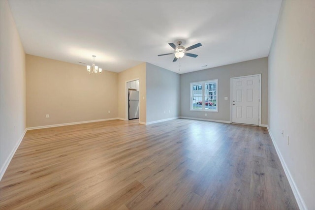 empty room with ceiling fan with notable chandelier and light wood-type flooring