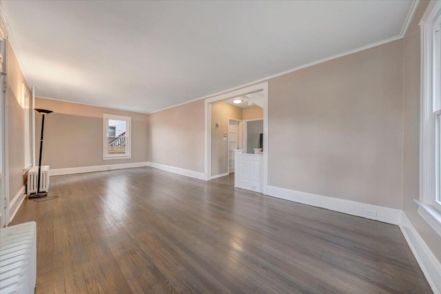 unfurnished living room featuring radiator heating unit, dark wood-type flooring, and ornamental molding