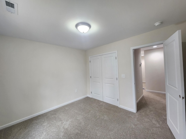 unfurnished bedroom featuring light colored carpet and a closet