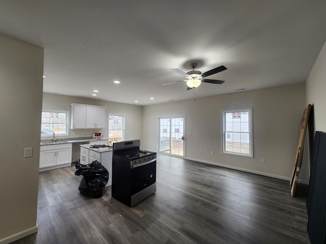 kitchen with gas stove, a healthy amount of sunlight, sink, white cabinets, and a kitchen island