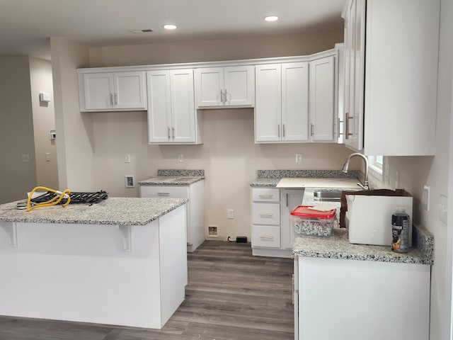 kitchen featuring white cabinets, a kitchen breakfast bar, and light stone counters