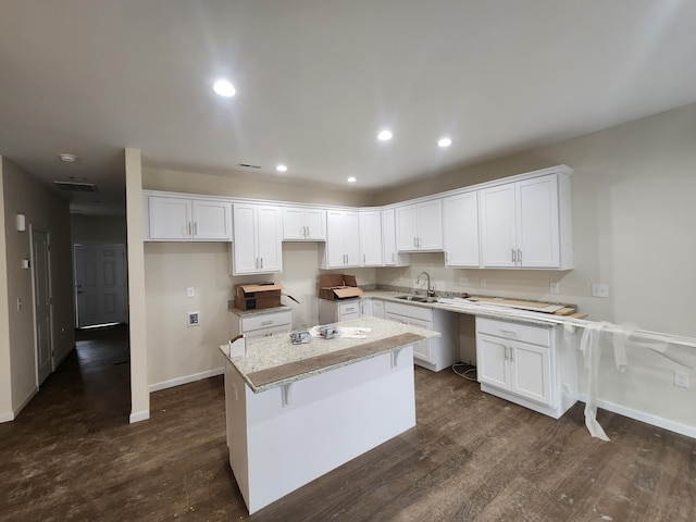 kitchen featuring dark hardwood / wood-style floors, a center island, a kitchen bar, and white cabinetry