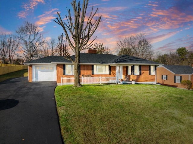 single story home with a lawn, covered porch, and a garage